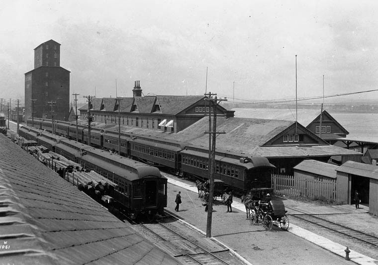 Trains sit beside the immigration sheds waiting for the immigrants to entrain [board] to travel to their final destinations.