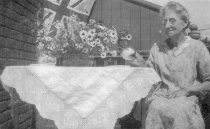 Photo of Ellen Mary Bartholomew in Montreal with a tablecloth she had made.